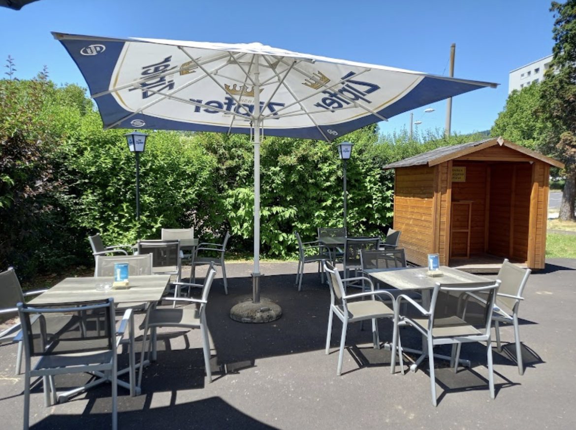 Gastgarten mit Sonnenschirm, Tischen und Holzhütte