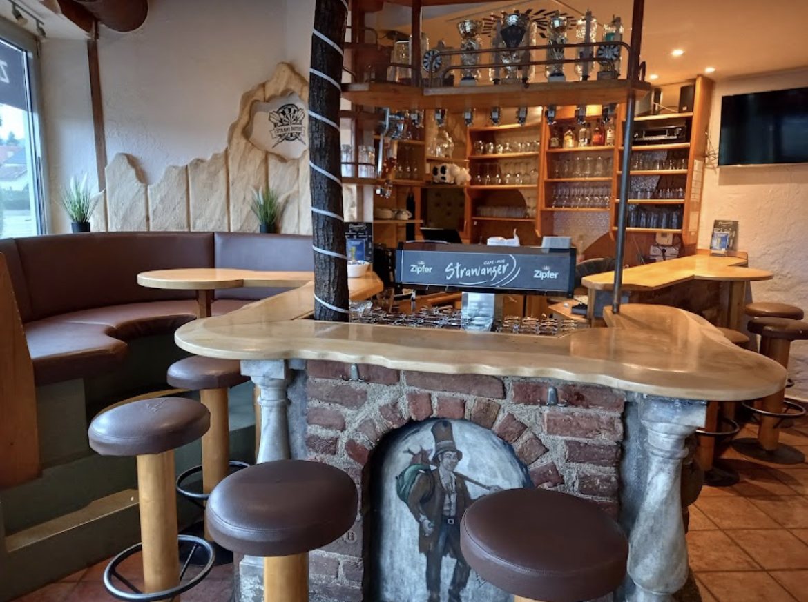 Die Holztheke mit Barhockern und dem gemalten Strawanzer